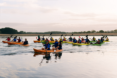 A group of kayakers paddling in a reservoir at sunset
