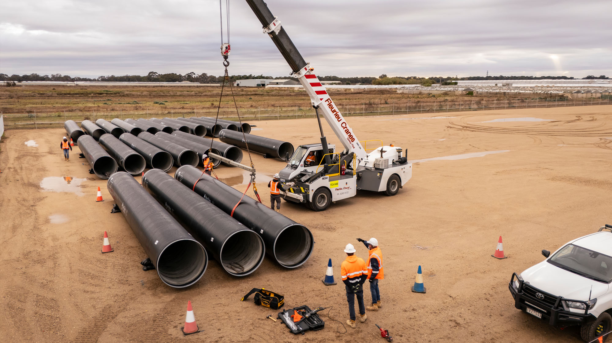 Large water main being delivered by crane to a large vacant block in Adelaide's north.