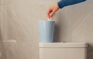 A lady's hand putting a tissue in the bin