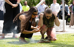 Two female SA Water team members  engaging in a smoking ceremony at a reconciliation event in Adelaide